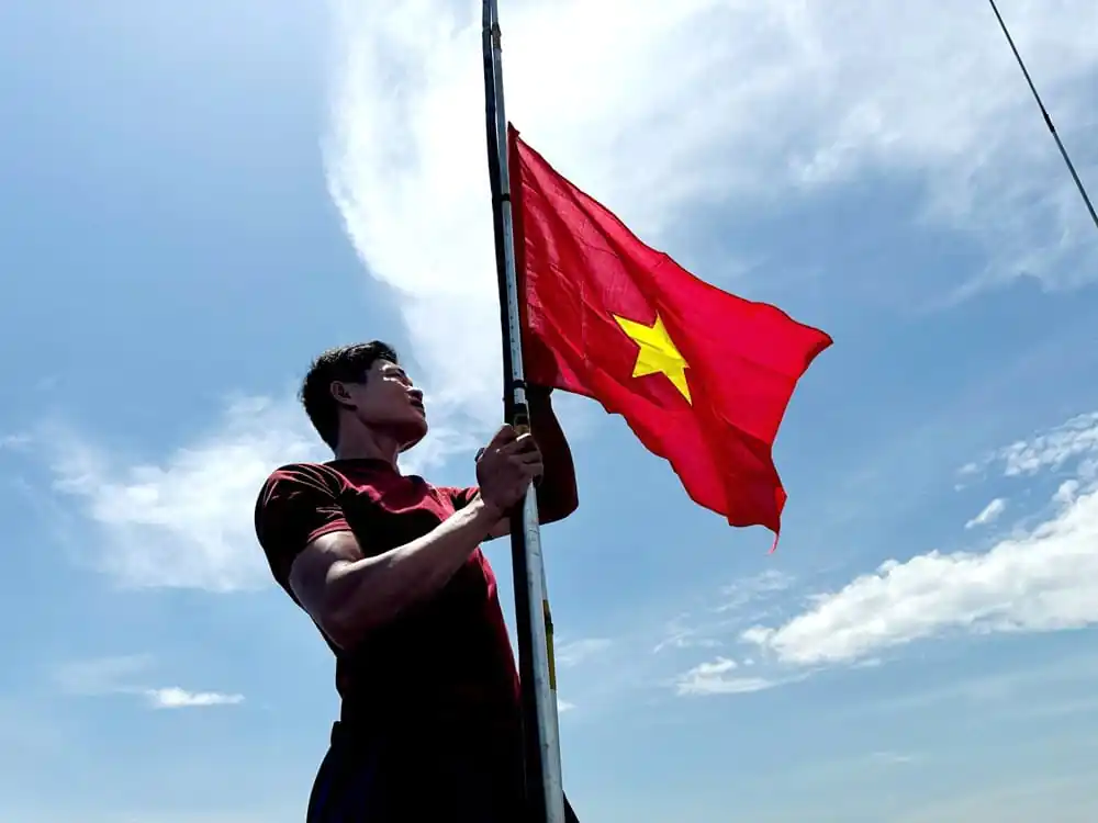 Hình tượng cánh tay vươn cao nắm chắc cờ Tổ quốc